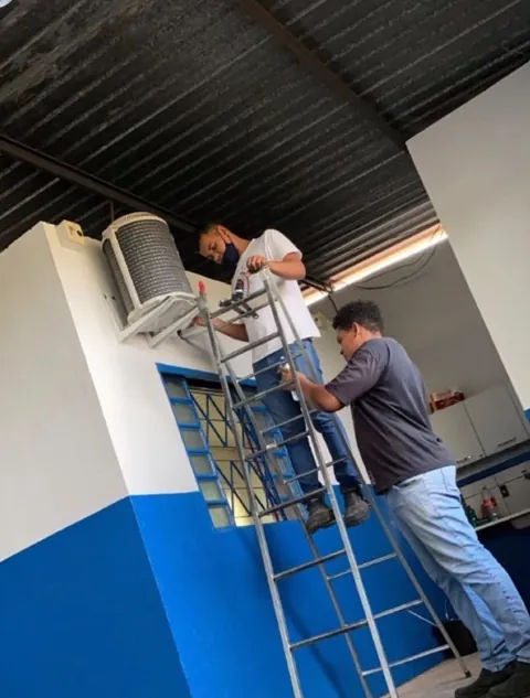 Técnicos instalando condensadora em um comércio